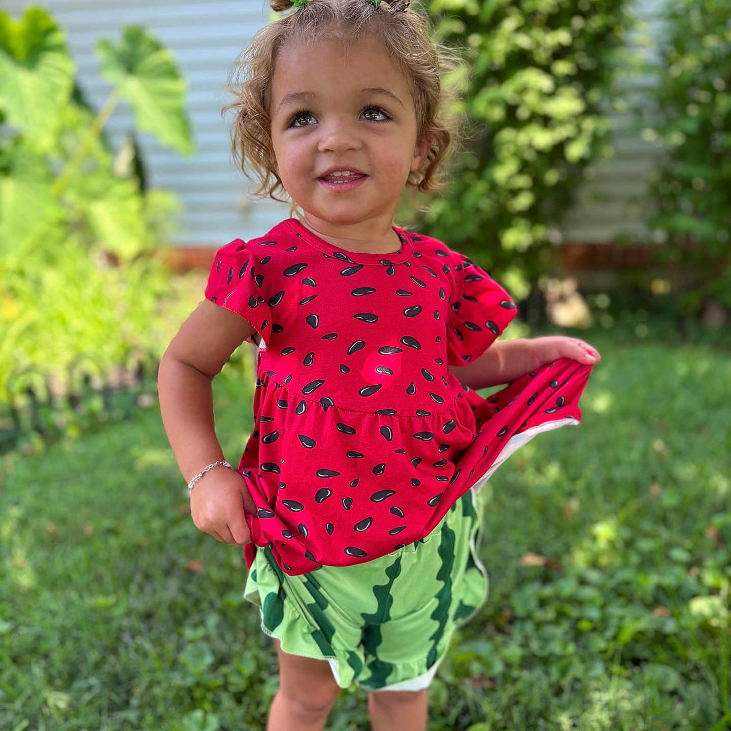 Wrenlee is registered to the contest to win money with this photo: barefoot, child, cute, daylight, garden, grass, greenery, hair_buns, happy, nature, outdoor, patterned_clothing, person, playful, portrait, red_clothing, smiling, summer, toddler, young_child