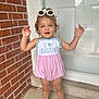 Wrenlee is registered to the contest to win money with this photo: toddler, child, girl, sunglasses, pink_dress, outdoor, brick_wall, door, smiling, standing, happy, summer, cute, footwear, playful, person, young_child, sunny, casual, portrait