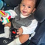 baby, car_seat, child, toy, smiling, infant, safety_belt, clothing, white_socks, cute, seat, car_interior, happy, portrait, young_child, sitting, colorful_toy, baby_girl, closeup, child_seat