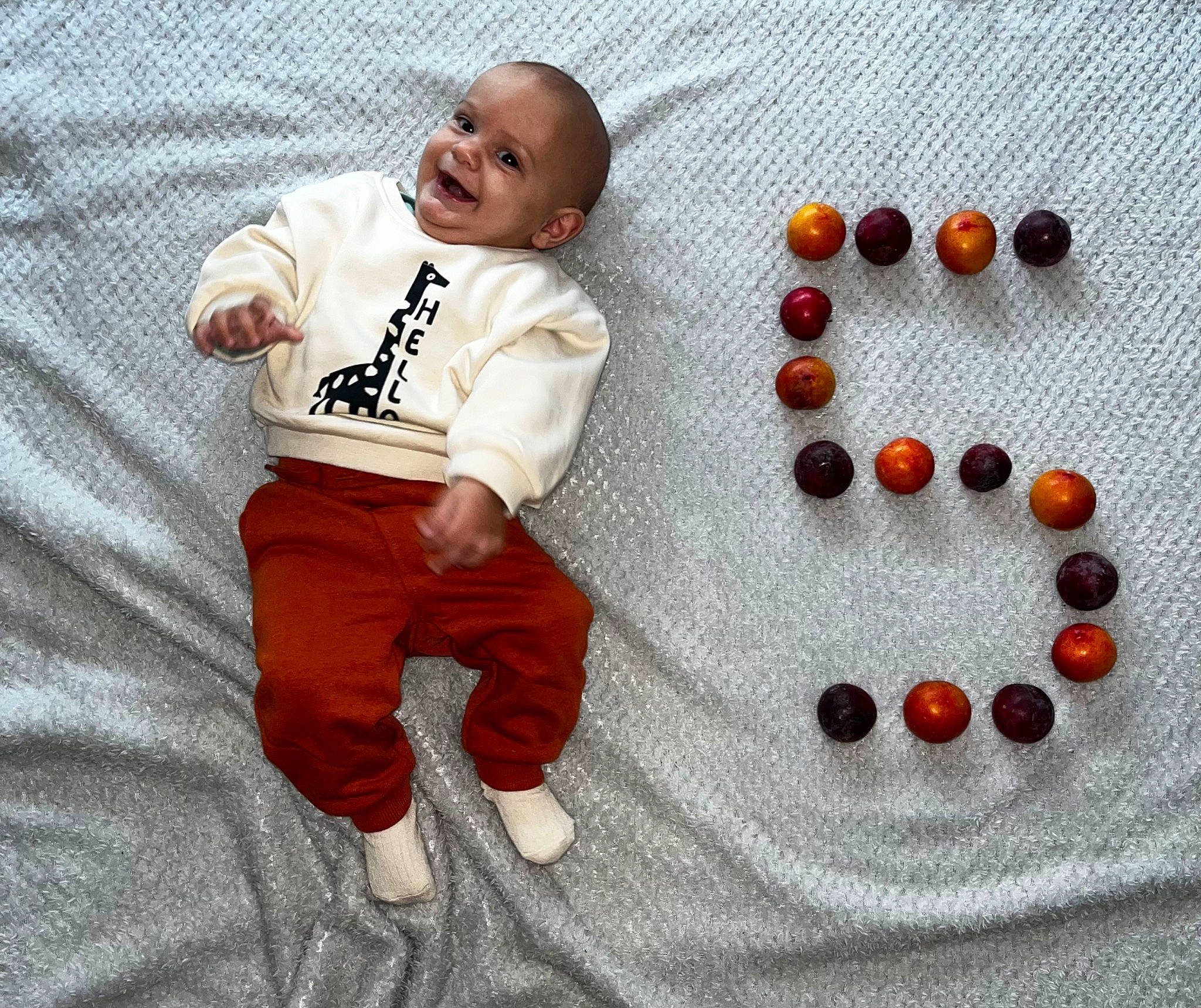 Gianni a rejoint le concours — aidez-le/la à gagner de superbes lots ! art, baby, baby_toddler_clothing, button, child, circle, fashion_accessory, flooring, font, happy, jewellery, natural_foods, orange, pattern, person, sleeve, smile, t_shirt, toddler, white