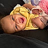 baby, infant, yellow_bib, bottle, pink_blanket, hand, face, smile, lying_down, clothing, baby_accessory, child, cute, happy, indoor, portrait, skin, newborn, cozy, baby_toy