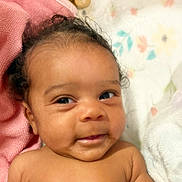 Kasani is registered to the contest to win money with this photo: baby, infant, face, smile, eyes, skin, hair, blanket, pink, fabric, soft, cute, closeup, portrait, child, newborn, lying_down, indoors, expression, adorable