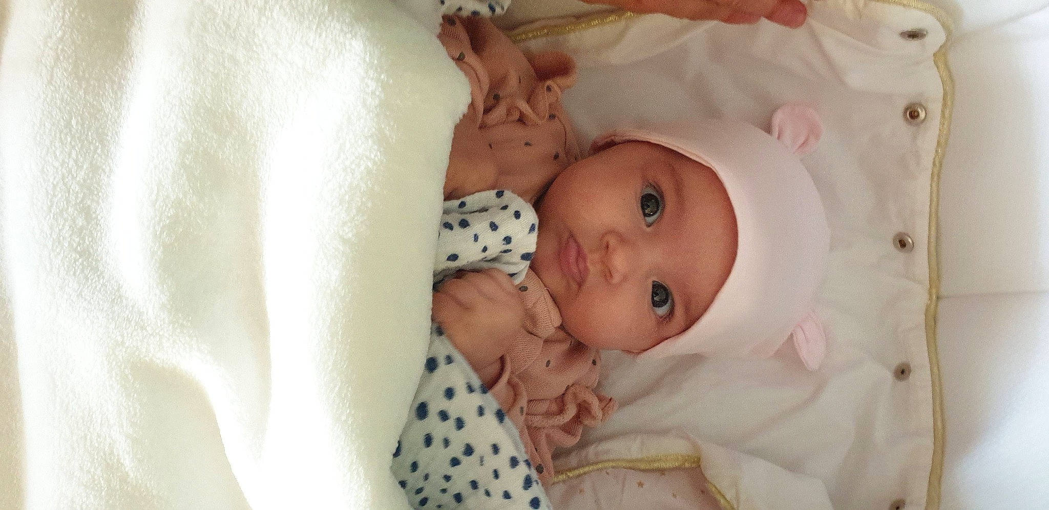 Inès participe au concours pour gagner de l'argent avec cette photo : baby, baby_products, baby_safety, baby_toddler_clothing, cheek, child, comfort, eye, eyelash, face, head, headwear, human_body, iris, linens, lip, nose, person, room, skin