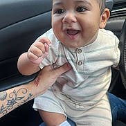 Luisniel joined the competition — help win amazing prizes! baby, child, smiling, happy, infant, striped_clothing, sneakers, car_interior, tattoo, hand, person, cute, face, seat, window, daylight, jeans, white_socks, closeup, portrait