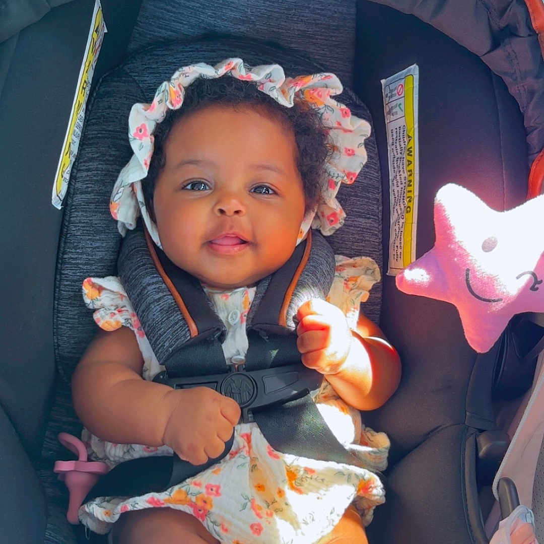Asiya joined the competition — help win amazing prizes! baby, car_seat, child, clothing, comfort, cute, face, floral, happy, headwear, indoors, infant, plush, safety, seat, seatbelt, small_person, smiling, star, toy