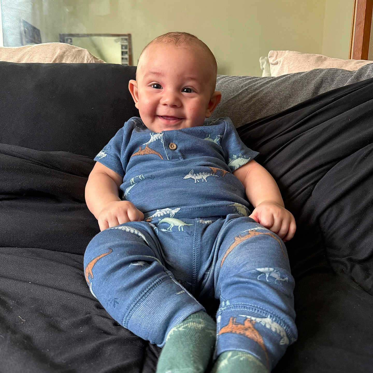 Drevaughn joined the competition — help win amazing prizes! baby, blue_clothing, child, couch, cozy, cute, dinosaur_pattern, face, feet, happy, head, home, indoor, infant, person, pillow, portrait, sitting, smiling, socks