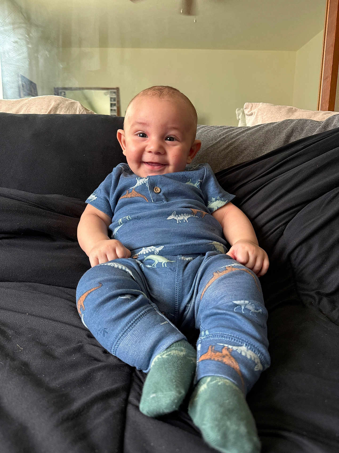 Drevaughn joined the competition — help win amazing prizes! baby, child, smiling, sitting, blue_clothing, dinosaur_pattern, couch, pillow, indoor, happy, infant, person, feet, socks, head, face, cute, cozy, home, portrait