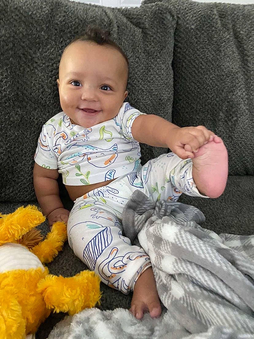 Caiden joined the competition — help win amazing prizes! baby, baby_toddler_clothing, cheek, child, comfort, couch, face, finger, foot, happy, head, joy, person, product, sitting, skin, sleeve, smile, sock, textile