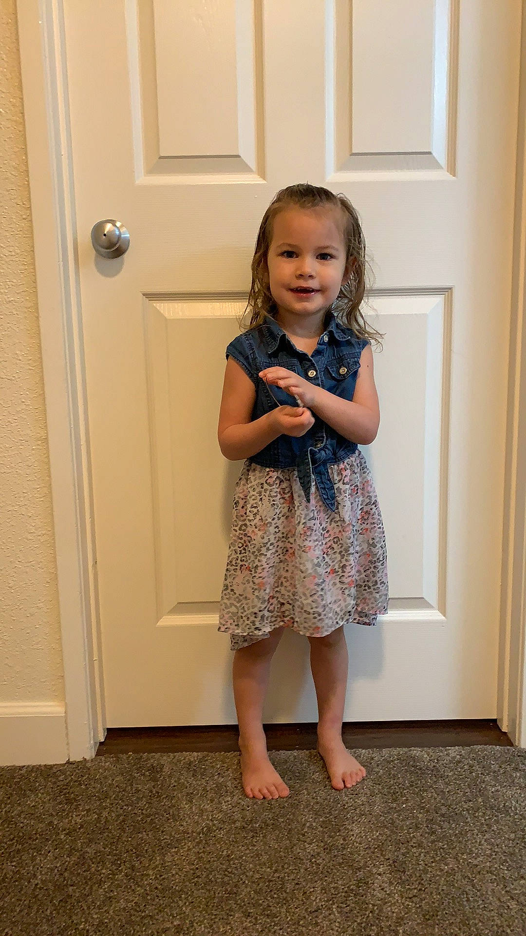 Madelynn is registered to the contest to win money with this photo: baby_toddler_clothing, child, clothing, day_dress, door, flooring, fun, happy, human_leg, joy, knee, one_piece_garment, pattern, person, shoulder, skin, sleeve, smile, standing, toddler