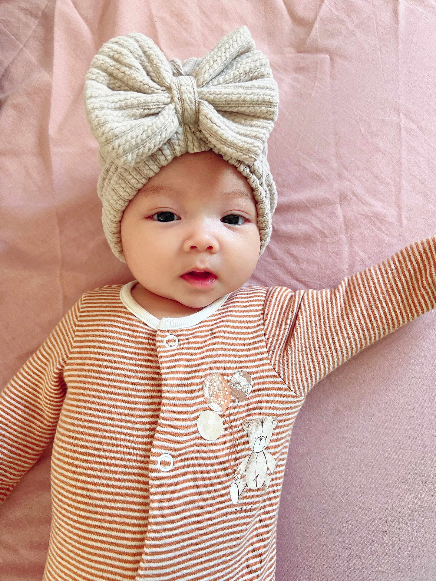 Isabella joined the competition — help win amazing prizes! baby, infant, child, striped_clothing, onesie, hat, bow, knit_hat, pink_blanket, teddy_bear, soft_texture, cute, lying_down, portrait, face, eyes, mouth, hand, cozy, sleepwear
