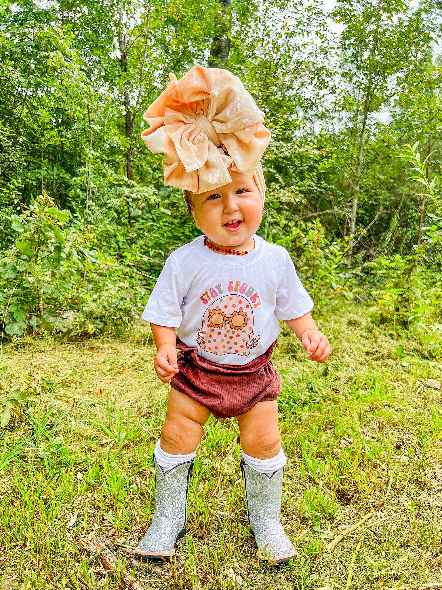 Luna is registered to the contest to win money with this photo: baby_toddler_clothing, face, footwear, gesture, grass, grassland, hair, happy, hat, head, headwear, human_body, leaf, natural_environment, people_in_nature, person, plant, shorts, sleeve, t_shirt