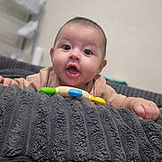 Caleb is registered to the contest to win money with this photo: baby, infant, child, portrait, face, eyes, open_mouth, smiling, indoor, blanket, couch, furniture, toy, teething_toy, clothing, hands, sitting, home, closeup, photography