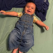 Enzo joined the competition — help win amazing prizes! baby, child, denim_overalls, smiling, lying_down, indoor, bed_sheet, blanket, clothing, cute, happy, infant, person, face, skin, foot, hand, toddler, casual, portrait