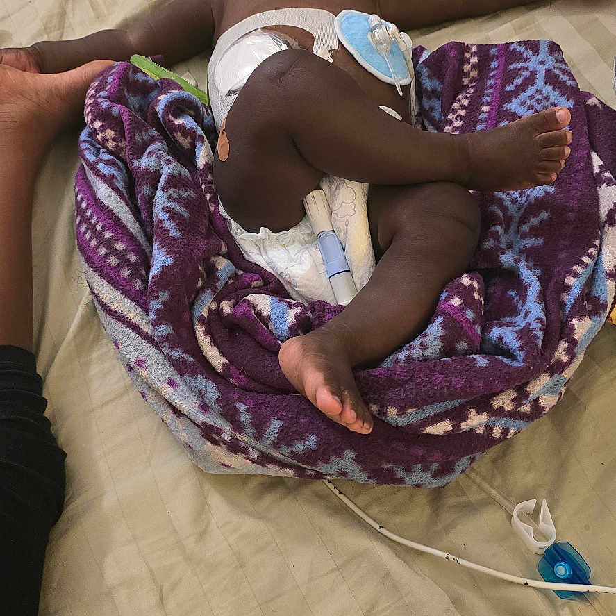 Josiah joined the competition — help win amazing prizes! baby, bed, blanket, box, brown_skin, child, diaper, foot, hand, healthcare, indoor, medical_device, paint, paper, purple, relaxing, resting, sleeping, striped_sheet, toy