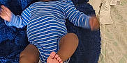 Josiah is registered to the contest to win money with this photo: baby, infant, blue_onesie, striped_clothing, blanket, bed, pillow, medical_tubing, child, indoor, person, legs, arms, feet, head, face, curious, lying_down, soft_texture, home