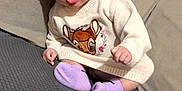 Lyvia a rejoint le concours — aidez-le/la à gagner de superbes lots ! baby, cartoon, child, clothing, couch, cozy, cute, deer, gray_surface, headband, headwear, indoor, infant, person, purple_socks, sitting, strawberry, surprised_expression, sweater, wide_eyes