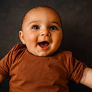 Jùlio a rejoint le concours — aidez-le/la à gagner de superbes lots ! baby, child, smiling, happy, face, portrait, infant, cute, clothing, brown_shirt, arms, closeup, studio, expression, joy, young, skin, head, eyes, background