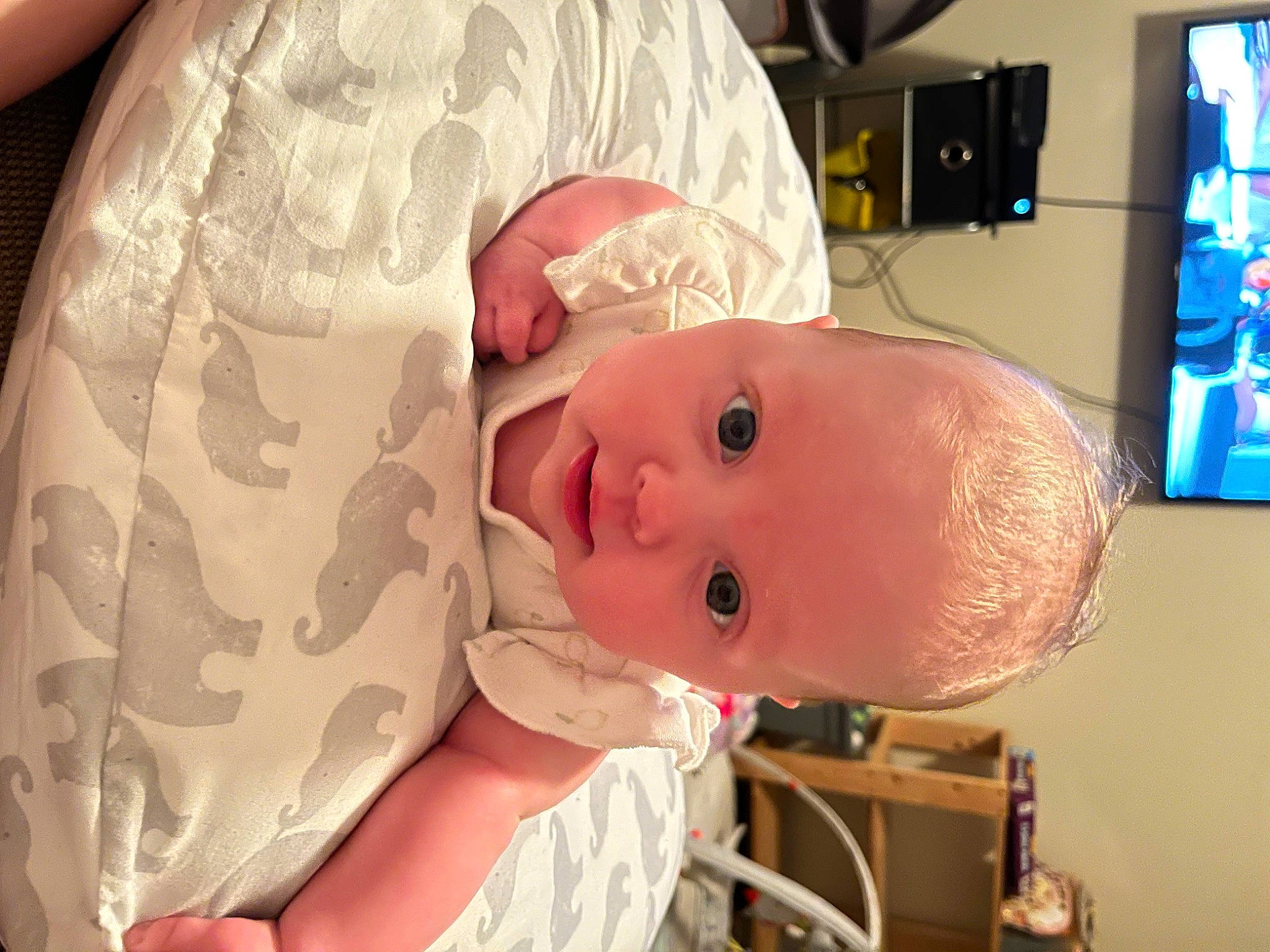 Everly is registered to the contest to win money with this photo: baby, baby_products, baby_safety, baby_toddler_clothing, cheek, child, comfort, eyebrow, eyelash, hat, human_body, nose, person, room, television, toddler