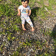 Rain joined the competition — help win amazing prizes! toddler, child, barefoot, outdoor, grass, wood_chips, sunlight, headband, black_bow, cartoon_clothing, sitting, playful_expression, nature, smiling, young_child, casual_wear, greenery, daylight, person, cute