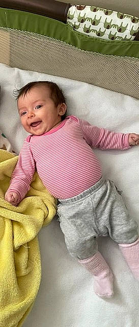 Leslie is registered to the contest to win money with this photo: arm, baby, baby_toddler_clothing, cheek, comfort, facial_expression, finger, happy, linens, neck, nose, outerwear, pattern, person, pink, skin, sleeve, smile, t_shirt, textile