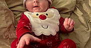 Bryce joined the competition — help win amazing prizes! baby, bed, bedding, bib, child, christmas, cozy, face, festive, holiday, indoors, infant, lying_down, pajamas, portrait, red_clothing, santa_hat, sitting, smiling, wide_eyed