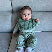 Giulia participe au concours pour gagner de l'argent avec cette photo : baby, infant, child, sitting, couch, sofa, clothing, bib, hair_clip, white_socks, green_outfit, indoor, portrait, cute, young, person, furniture, face, head, expression