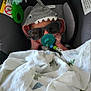 baby, car_seat, pacifier, sunglasses, hoodie, shark_costume, blanket, plush_toy, infant, child, cute, sleeping, comfort, indoors, accessory, face, headwear, toy, rest, cozy