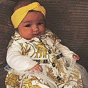 Kamyla participe au concours pour gagner de l'argent avec cette photo : baby, infant, headband, dress, patterned_clothing, couch, sofa, textured_fabric, barefoot, cute, child, portrait, indoor, relaxed, seated, small_hand, small_foot, comfortable, fashion, cozy