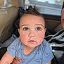baby, blue_clothing, car, car_seat, casual_wear, child, curious, cute, dinosaur_pattern, expression, eyes, face, holding_hand, indoors, infant, natural_light, person, portrait, rosy_cheeks, young_child
