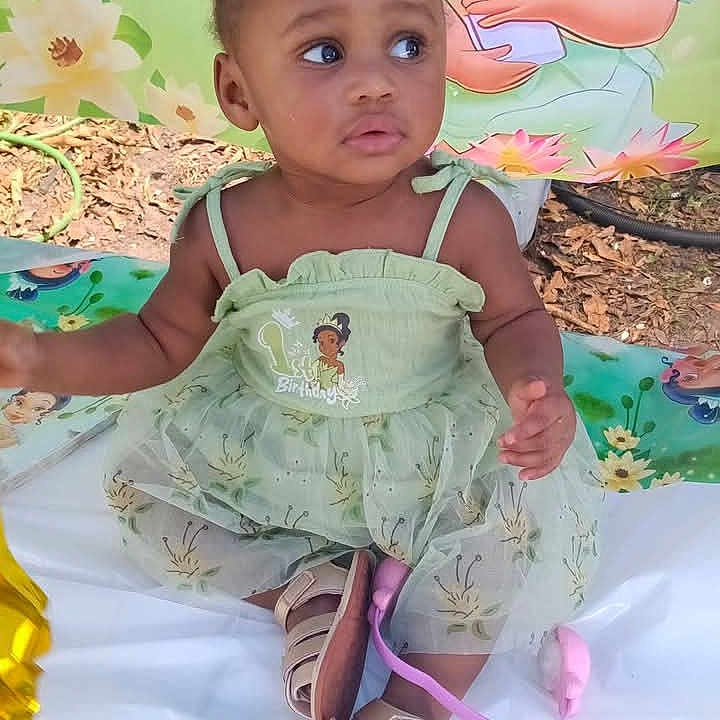 Na'Ryhia Smith joined the competition — help win amazing prizes! toddler, child, dress, headband, outdoor, sitting, cartoon_backdrop, green, footwear, playful, colorful_mat, young_child, portrait, cute, baby, happy, nature, celebration, smiling, summer