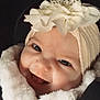 adorable, apparel, baby, child, closeup, cute, expression, face, flower, fur_coat, happy, headband, headwear, indoors, infant, person, portrait, smile, warm_clothing, young_child