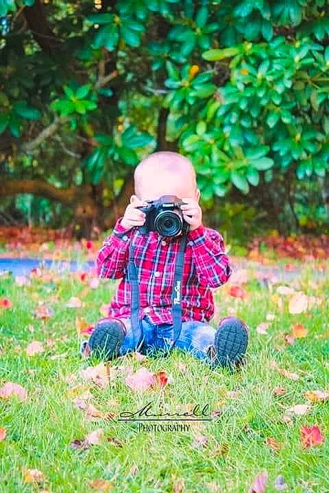 Kolton is registered to the contest to win money with this photo: baby, baby_toddler_clothing, botany, deciduous, doll, electric_blue, grass, groundcover, happy, lawn, magenta, pattern, people_in_nature, person, plaid, plant, purple, tartan, toddler, toy
