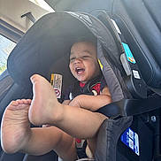 August is registered to the contest to win money with this photo: baby, car_interior, car_seat, child, clothing, cute, feet, happy, infant, laughing, person, playful, safety, seat, seatbelt, smiling, sunlight, toddler, vehicle, window