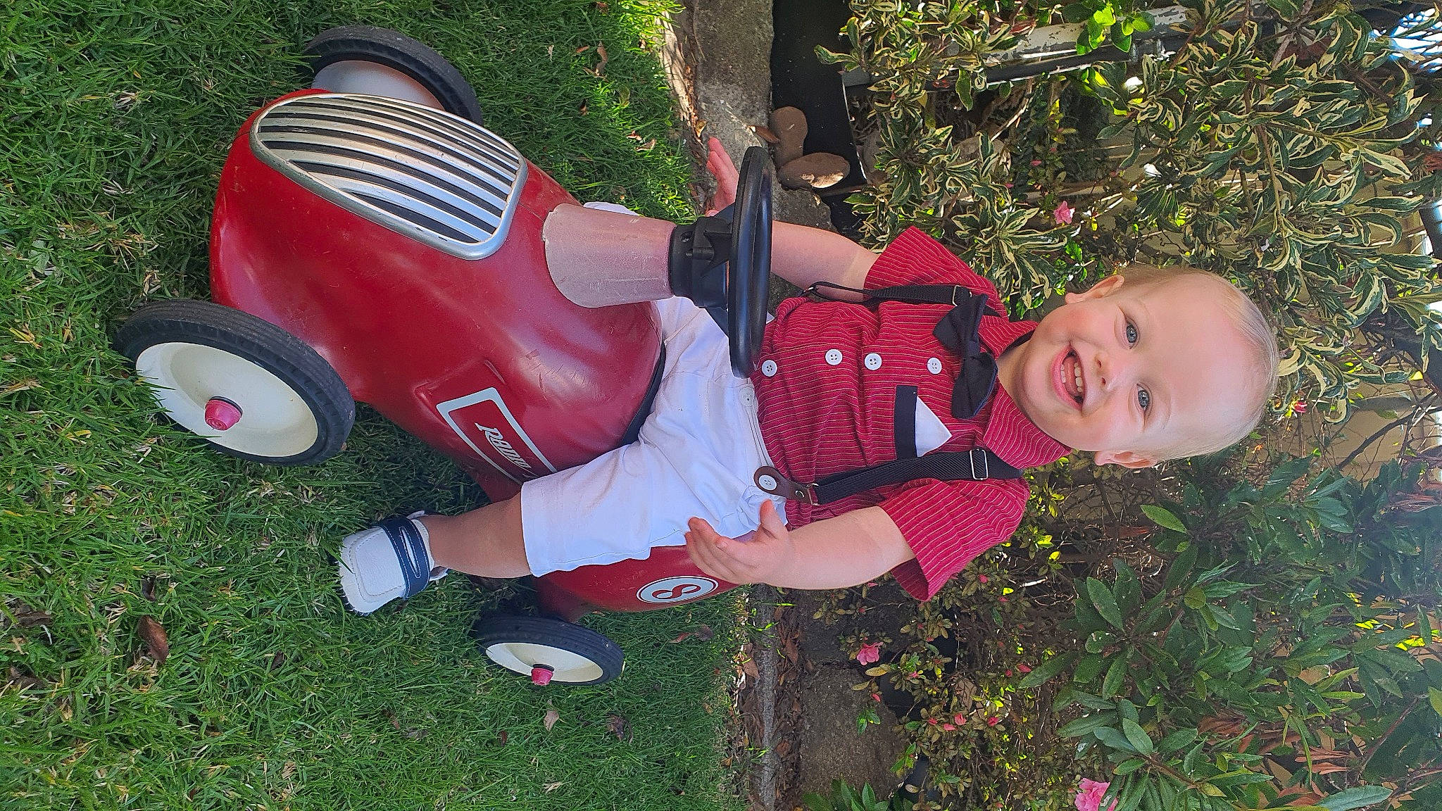 Nixon is registered to the contest to win money with this photo: automotive_design, automotive_tire, automotive_wheel_system, baby_toddler_clothing, classic_car, fender, fun, grass, happy, joy, leisure, motor_vehicle, people_in_nature, person, plant, riding_toy, smile, tire, toddler, tree