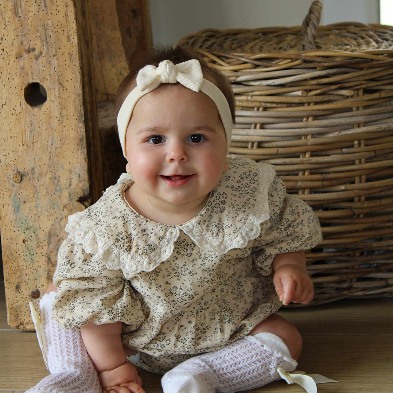 Apolline participe au concours pour gagner de l'argent avec cette photo : baby, basket, bodypart, bonnet, cap, clothing, dress, face, finger, hand, hardwood, hat, head, hosiery, person, photography, portrait, sitting, sock, wood