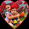 Emiely is registered to the contest to win money with this photo: child, children, baby, outdoor, grass, toy, heart_frame, hugging, smiling, headband, red_clothing, purple_clothing, playful, cute, portrait, family, happy, park, summer, sitting