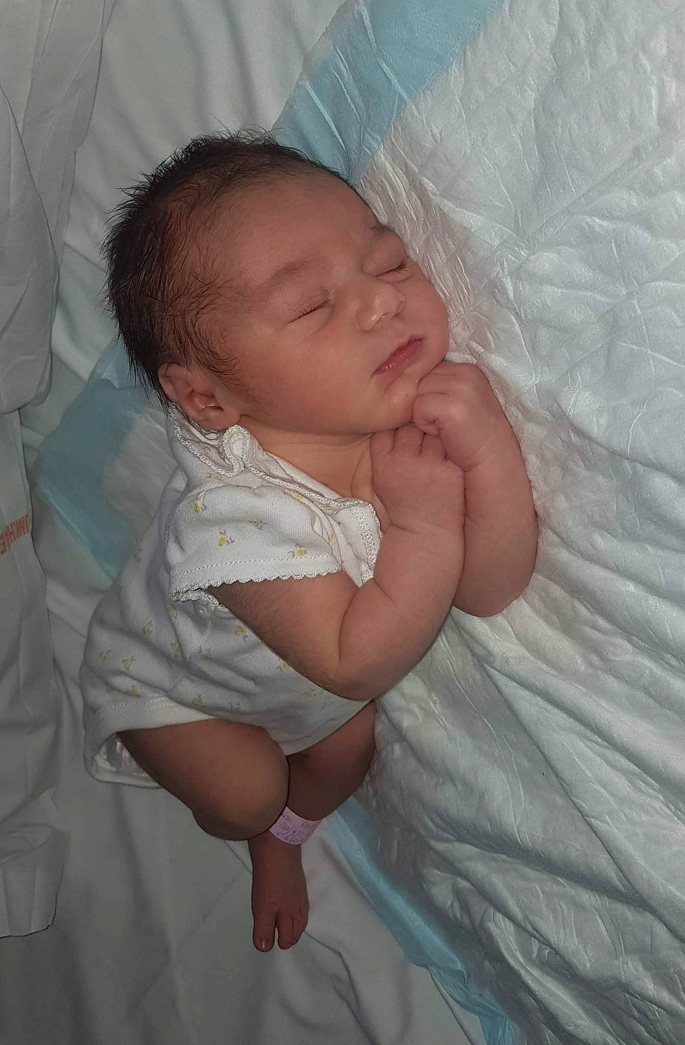 Alicia participe au concours pour gagner de l'argent avec cette photo : arm, baby, baby_toddler_clothing, bed, bedding, cheek, child, comfort, eye, finger, gesture, hand, happy, human_body, iris, linens, person, skin, textile, thumb