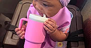 Erynomie is registered to the contest to win money with this photo: baby, child, girl, headband, pink, sippy_cup, high_chair, clothing, socks, patterned_dress, indoor, seated, curious, cute, toddler, purple, bow, hands, face, table