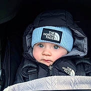 Ralph is registered to the contest to win money with this photo: baby, child, face, blue_eyes, hat, beanie, jacket, north_face, blanket, stroller, winter_clothing, cold_weather, outdoor, closeup, portrait, cute, warm, infant, fashion, bundle