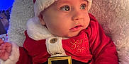 Ralph is registered to the contest to win money with this photo: baby, blanket, blue_lights, child, christmas, cozy, cute, face, festive, hand, hat, holiday, indoors, infant, portrait, red_clothing, santa_claus_costume, smiling, soft_texture, white_fur_trim