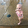toddler, child, water_fountain, play, swimsuit, barefoot, outdoor, water, fun, summer, curious, wet_surface, colorful, young_child, reaching, happy, park, fountain, playground, daytime