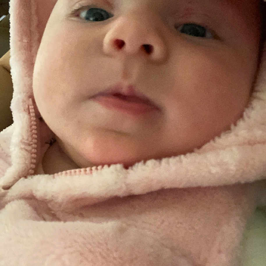 Kinsley is registered to the contest to win money with this photo: baby, blanket, bonnet, clothing, coat, face, hat, head, hood, hoodie, jacket, knitwear, newborn, person, photography, portrait, quilt, sweater, sweatshirt, towel