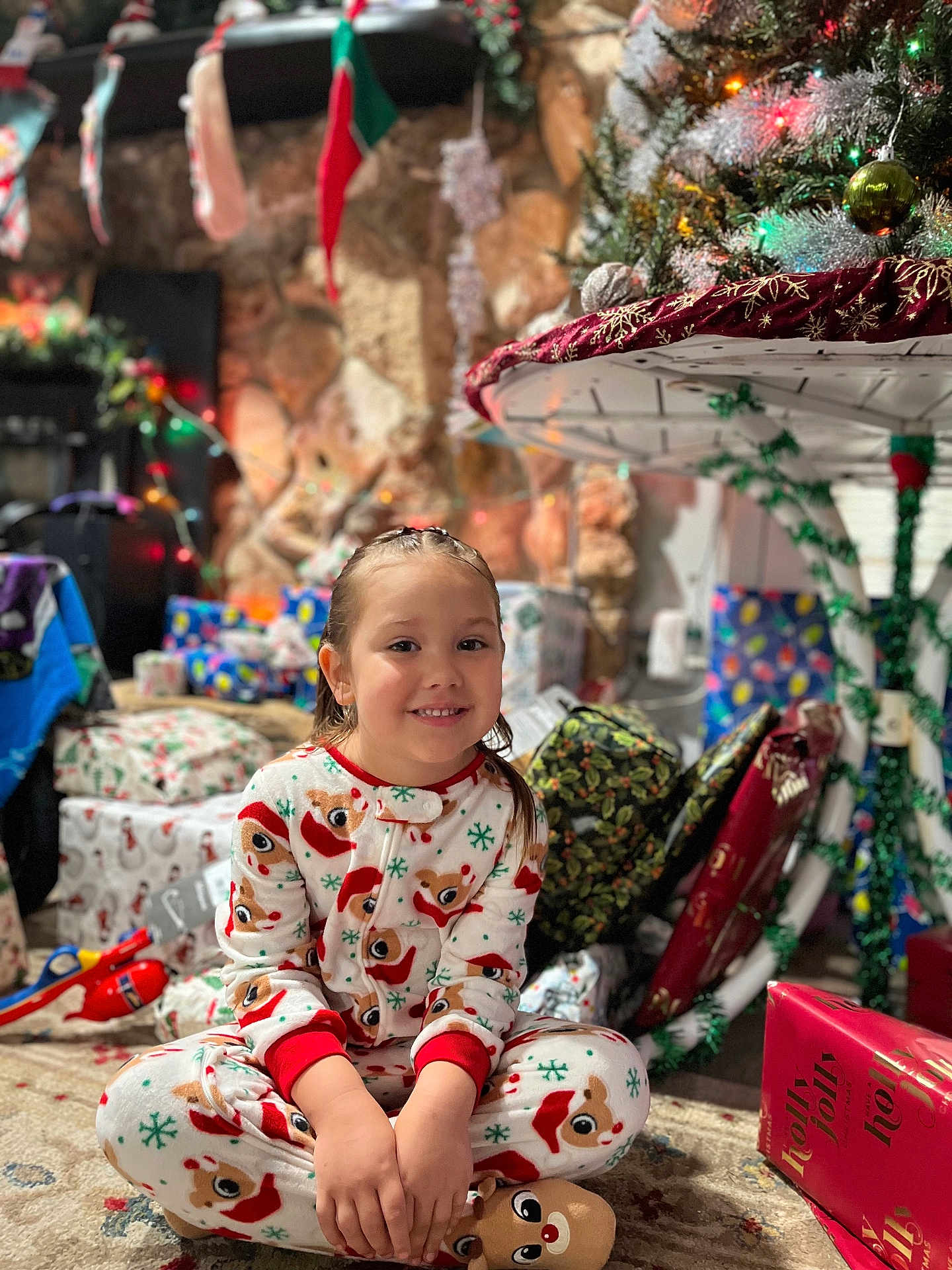 Leilani joined the competition — help win amazing prizes! child, pajamas, reindeer, christmas_tree, presents, carpet, fireplace, stockings, holiday, smiling, indoors, decorations, girl, festive, holiday_lights, wrapped_gifts, sitting, cozy, celebration, happy