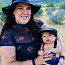Typhuryn is registered to the contest to win money with this photo: woman, baby, hat, outdoor, mountains, nature, smile, holding, child, portrait, clothing, suspenders, cap, bracelet, tattoo, earrings, grass, trees, scenery, family