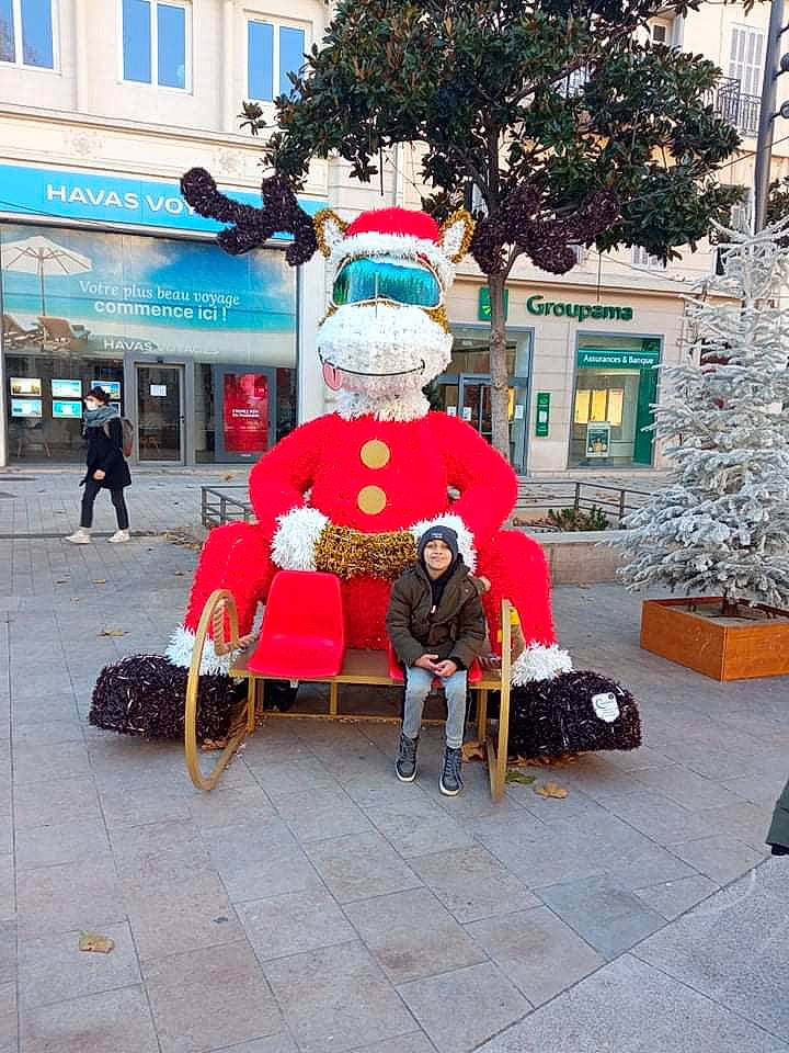 Rayan participe au concours pour gagner de l'argent avec cette photo : art, city, costume_hat, event, fictional_character, headwear, holiday, human_settlement, leisure, person, recreation, road, road_surface, santa_claus, sidewalk, snapshot, street, tree, urban_area, wheel