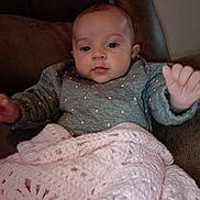 Alice is registered to the contest to win money with this photo: baby, infant, child, blanket, crochet, sweater, polka_dot, hand, face, eyes, mouth, chair, couch, indoor, portrait, cute, cozy, soft, pink, brown