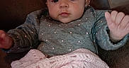 Alice is registered to the contest to win money with this photo: baby, infant, child, blanket, crochet, sweater, polka_dot, hand, face, eyes, mouth, chair, couch, indoor, portrait, cute, cozy, soft, pink, brown