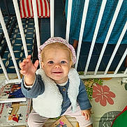 Chjara participe au concours pour gagner de l'argent avec cette photo : toddler, child, smiling, indoor, playmat, toys, books, vest, headband, socks, floor, colorful, baby, furniture, safety_bars, happy, cute, person, reaching, seated