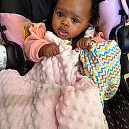 Joy Ivy is registered to the contest to win money with this photo: baby, child, car_seat, blanket, pink, colorful, zigzag_pattern, clothing, curly_hair, face, hands, indoor, portrait, seatbelt, cute, infant, expression, soft_texture, person, young