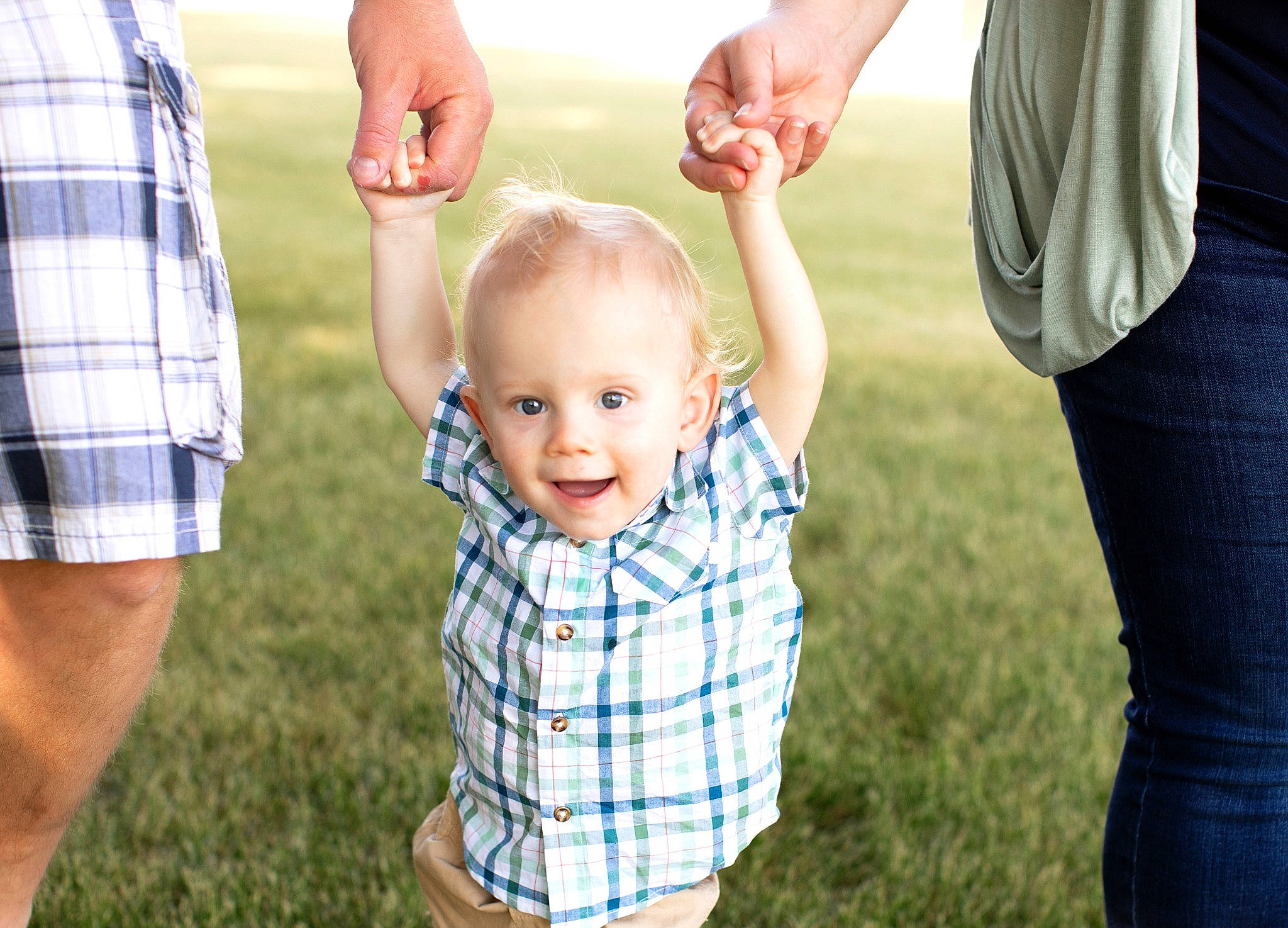 Judson is registered to the contest to win money with this photo: baby, eye, face, finger, fun, gesture, grass, hair, hand, happy, holding_hands, human_body, people_in_nature, person, plaid, plant, smile, standing, tartan, toddler